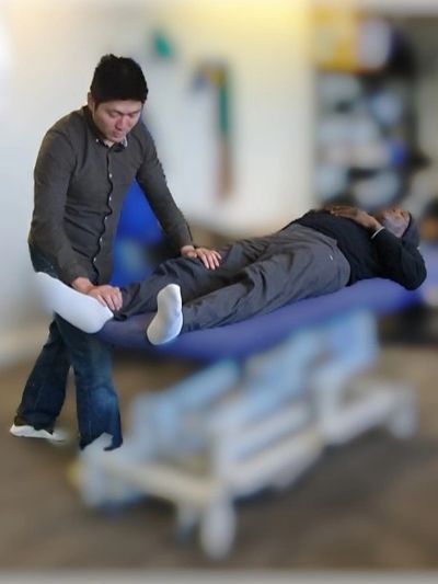 A therapist assists a patient in leg exercises on a treatment table.