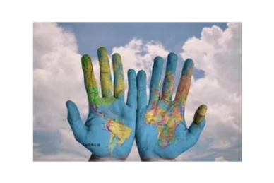 Two hands painted with a world map against a cloudy sky.