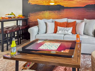 Cozy living room with a sunset mural and Infinity Game table at Sunny Side Falls in Roark Creek Resort, Branson Missouri.