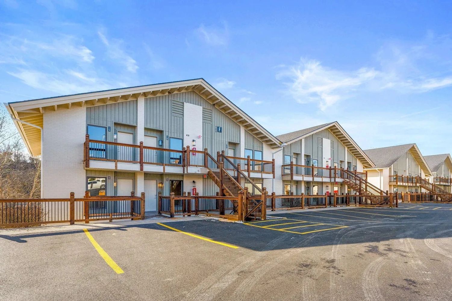 Modern two-story apartment complex with wooden railings and clear blue skies at Sunny Side Falls in Roark Creek Resort, Branson Missouri.