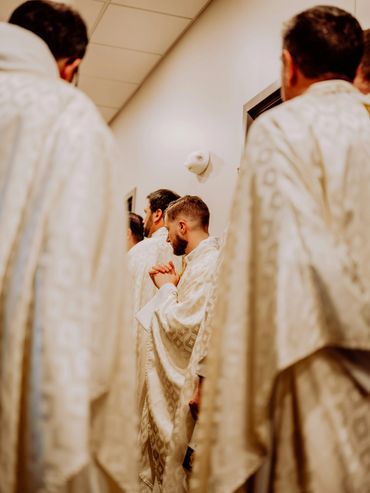 Men dressed in white religious robes, one praying.