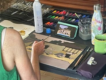 Person painting a landscape on canvas with art supplies around.
