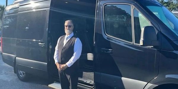 A professional driver next to a Mercedes-Benz Passenger Sprinter Van Airport Shuttle
