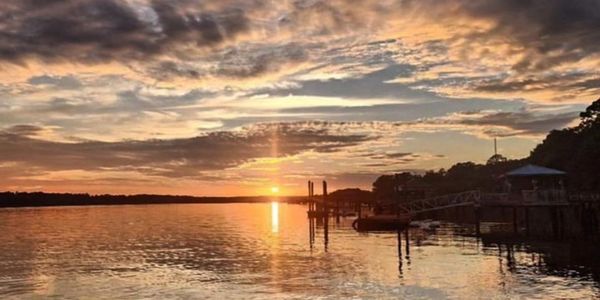Sunset along the May River in Bluffton South Carolina. The sun is reflecting off of calm water.