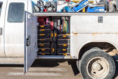 Open compartment of a utility truck filled with organized toolboxes and equipment.