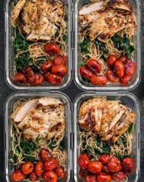 Meal prep containers with grilled chicken, cherry tomatoes, and spinach pasta.
