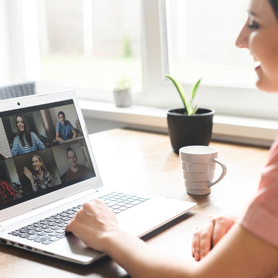 Woman video chatting with friends on a laptop at home.