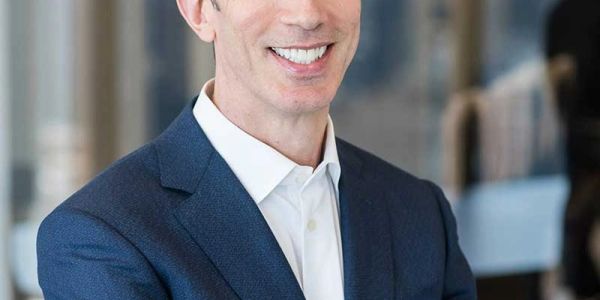 Man in business attire smiling confidently.