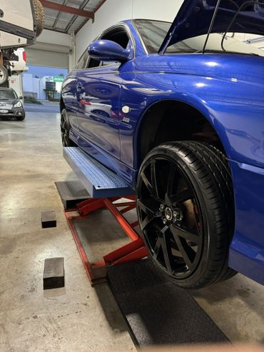 Blue car on a lift with black wheels in a garage.