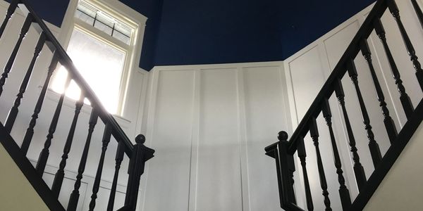 Black railing, white wainscoting and navy blue wall accent.