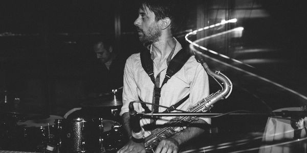 A black and white photo of a saxophonist playing on stage.
