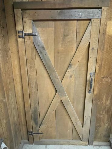 Wood door with hand-forged wrought iron hinges and handle