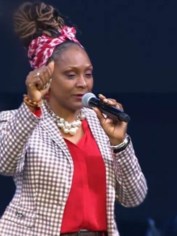 Woman speaking into a microphone with raised fist.