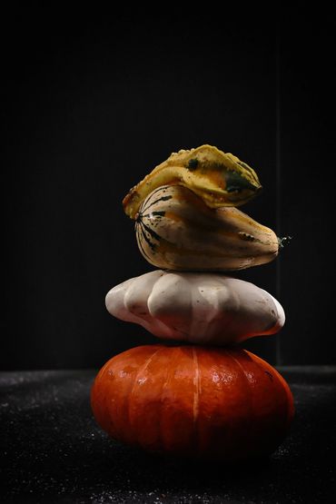 Stack of colorful pumpkins against a dark background.