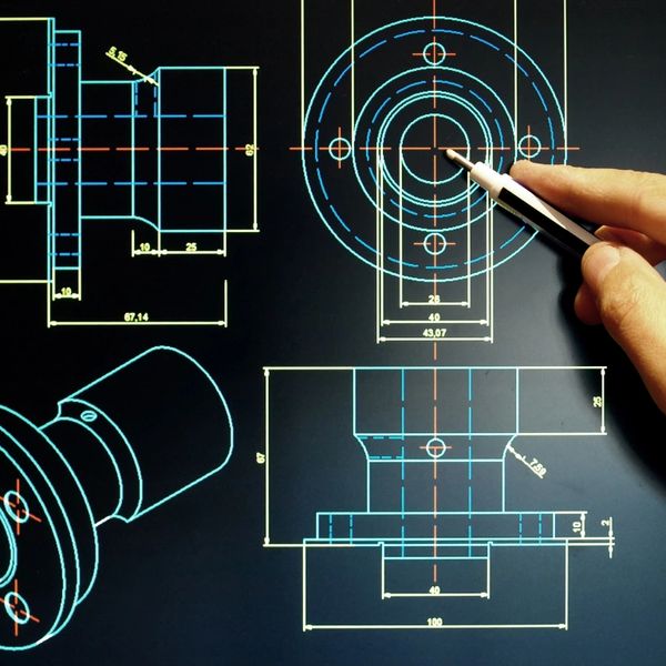 Hand pointing at mechanical CAD drawings on a computer screen with dimensions.