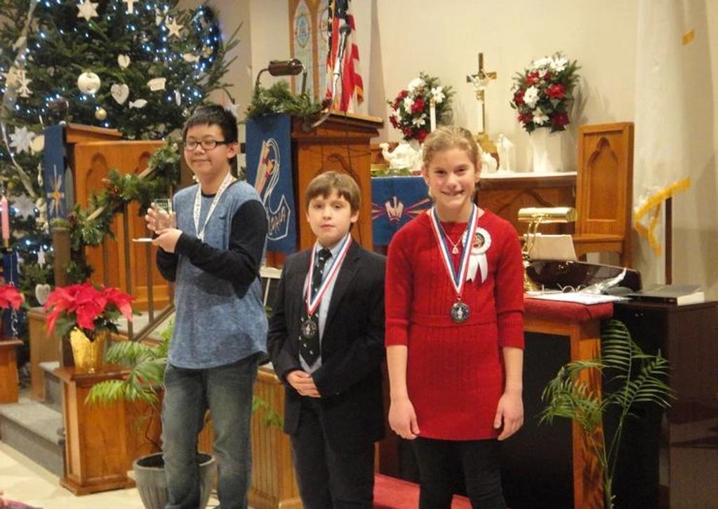 3 students receiving trophies and medals