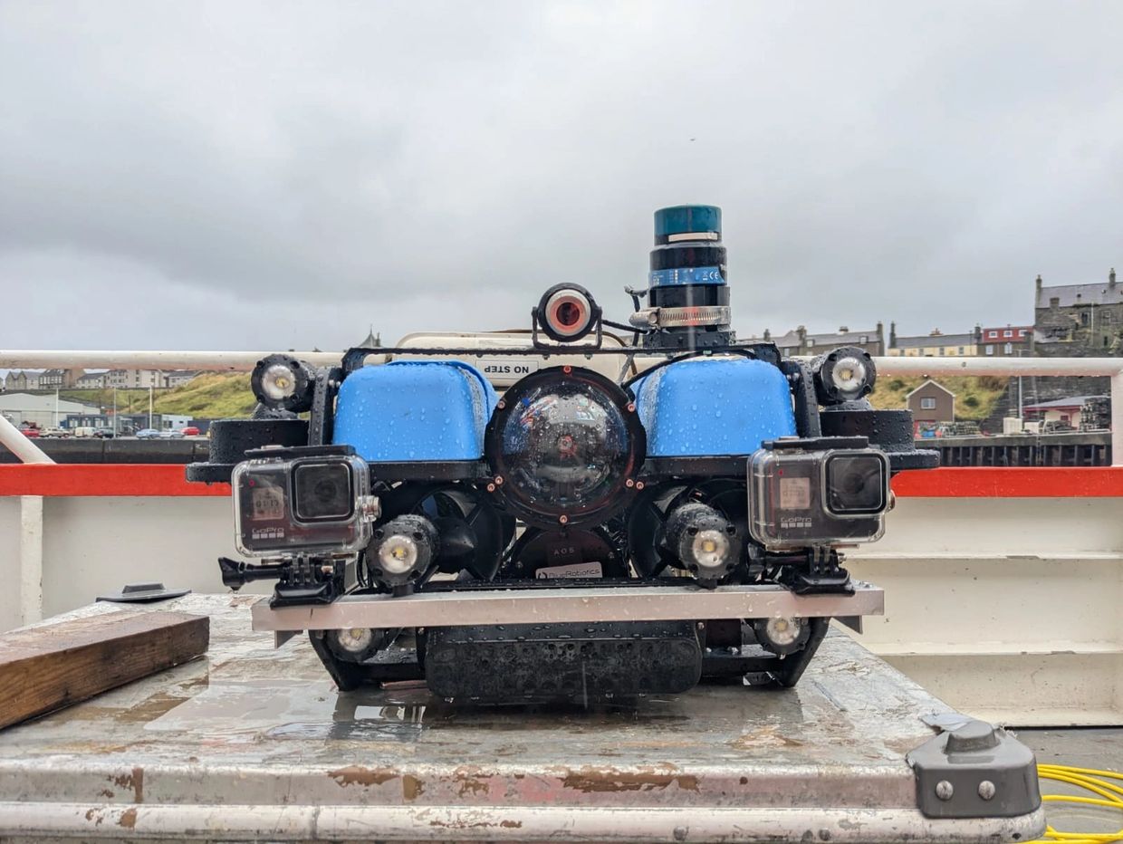Underwater drone with cameras and sensors on a wet surface outdoors.