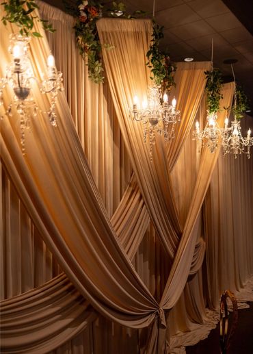 Elegant draped curtains with chandeliers and floral decorations.
