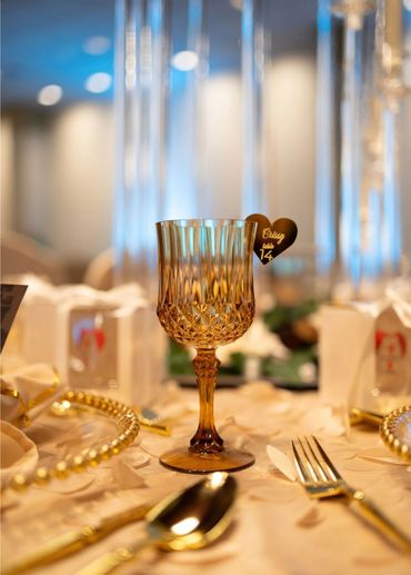 Elegant amber glass with a heart-shaped table number tag on a decorated dining table.