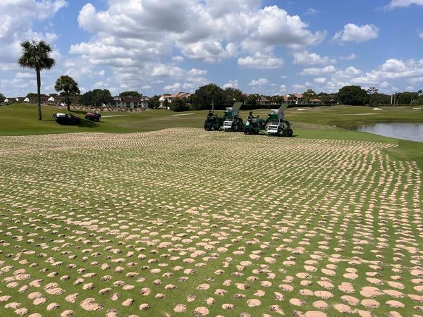 2 Drill and Fill Aerators drilling and backfilling on a golf course green.