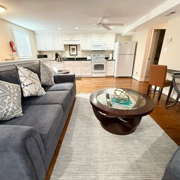 Cozy living room with gray sofas and a modern kitchen in the background.