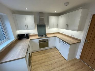Modern kitchen with wooden countertops, white cabinets, and built-in appliances.