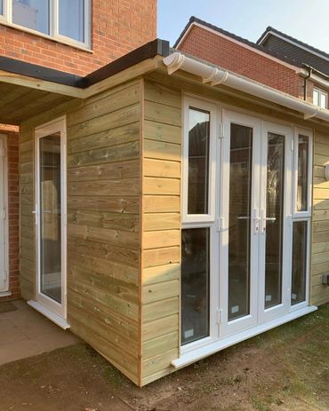 New wooden garden room extension with white framed glass doors and windows.