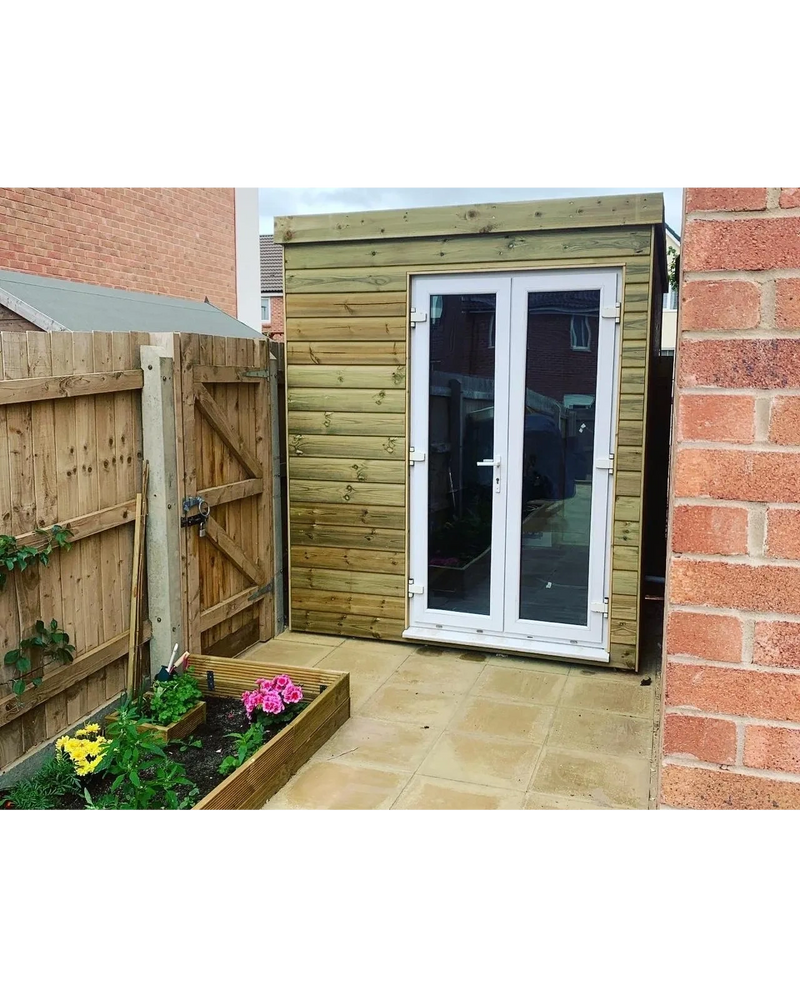 A small garden shed with glass doors in a paved backyard.
