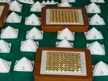 Man meditating with pyramid models on green mat.