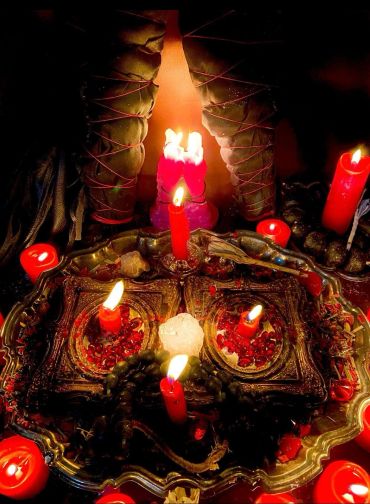 Red candles, crystals, and mystical arrangement on an ornate tray.