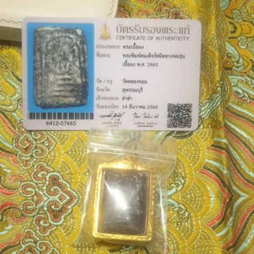 Certificate and amulet with Thai text on patterned fabric.