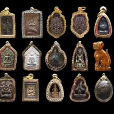 Collection of Thai amulets and figurines against black background.