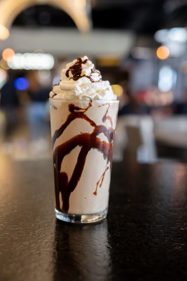 malteada de chocolate, con crema batida, en un vaso de vidrio.