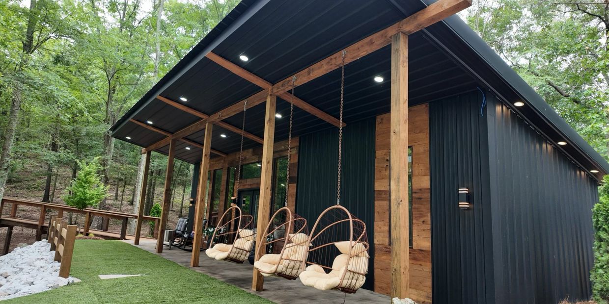 Modern cabin porch with hanging chairs and wood accents in a forest setting.