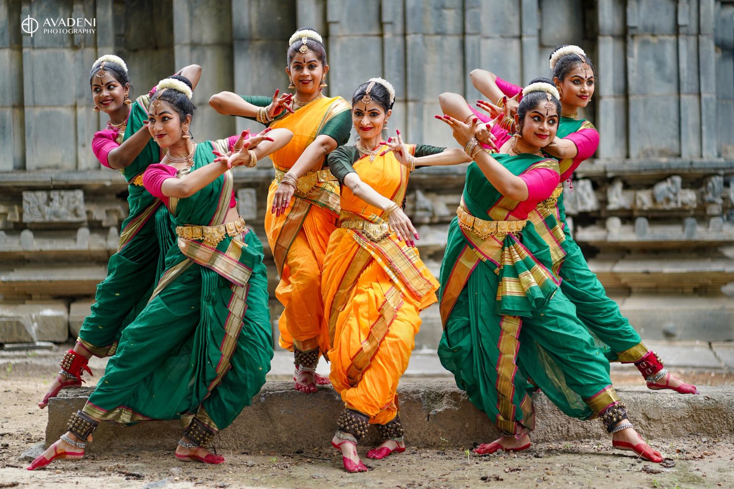 Group of traditional Indian dancers in colorful attire performing a classical dance pose.