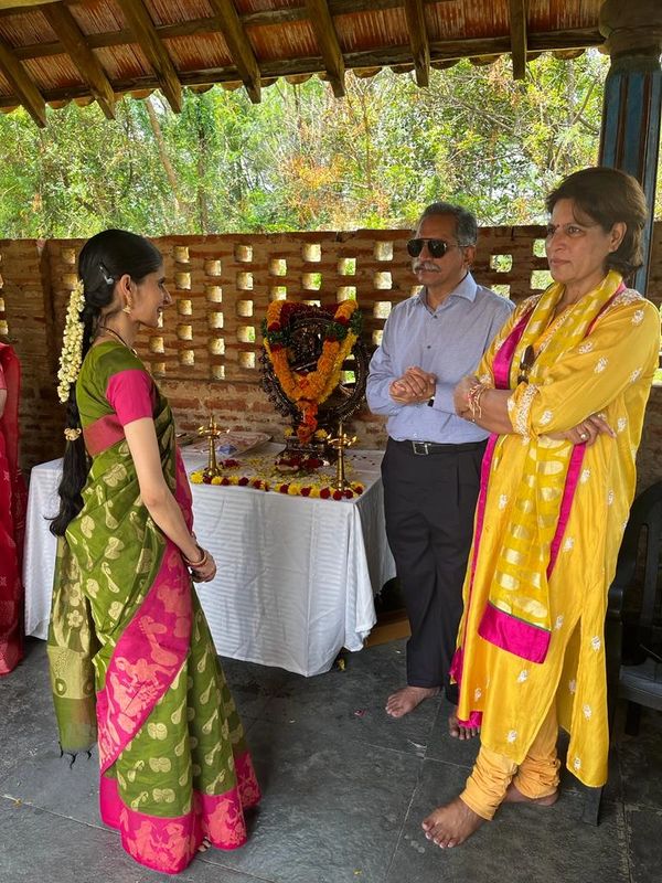 Three people engaged in a traditional ceremony near a decorated idol.