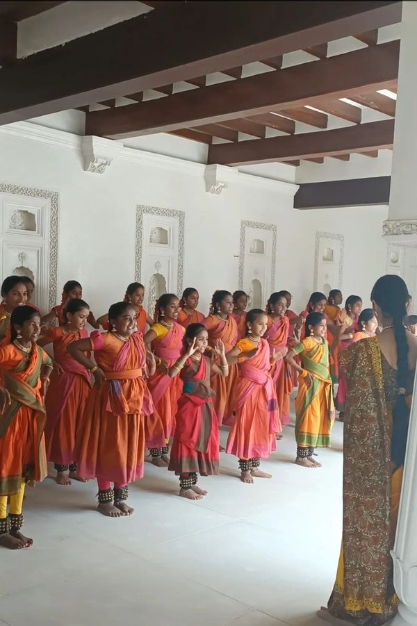 Young girls practicing traditional Indian dance in colorful attire indoors.