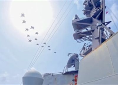Aviones militares en formación sobre un buque de guerra.