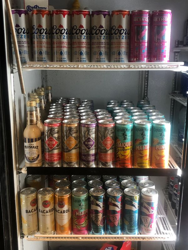 A fridge stocked with various alcoholic beverages in cans and bottles.