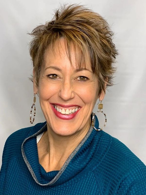 Sharon is wearing a blue blouse and two circle earrings.