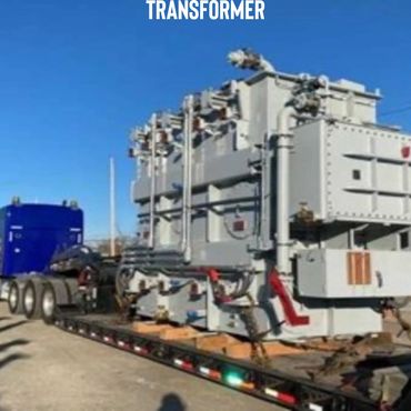 Large electrical transformer being transported on a flatbed truck.
