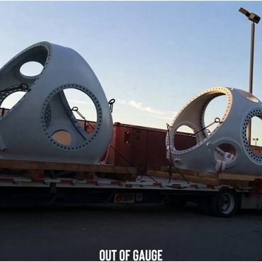 Large industrial metal components secured on a flatbed truck for transport.