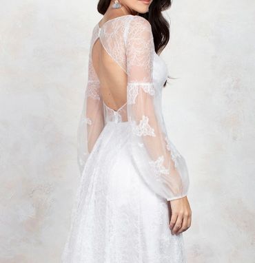 Elegant white lace dress with sheer long sleeves and an open back design.