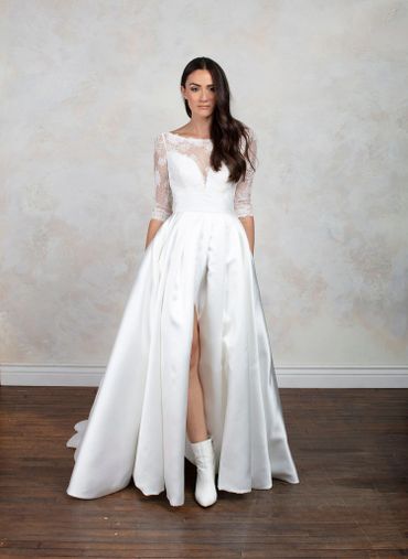 Model in a modern white wedding dress with lace sleeves and boots.
