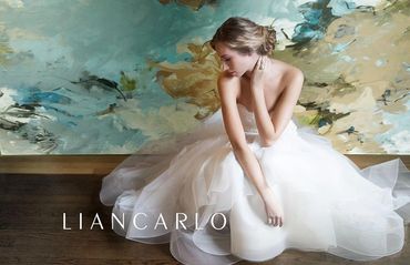 A bride in a white gown poses gracefully against an abstract background.