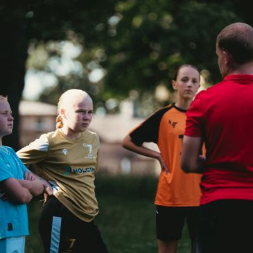 Young soccer players listening to a coach on the field.