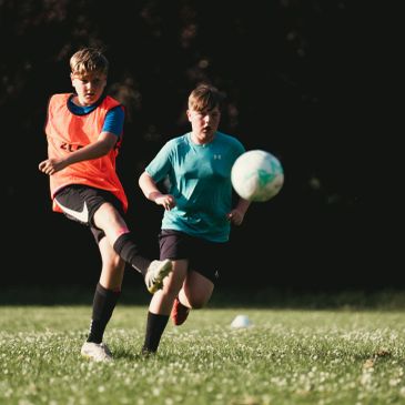 Two boys playing soccer outdoors.