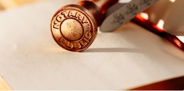 A notary public stamp on a document with a pen nearby.