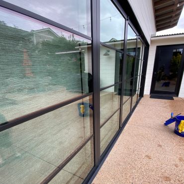 Modern black-framed glass doors and windows with reflections.