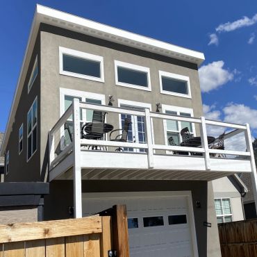 Modern townhouse with balcony and garage under a clear blue sky.